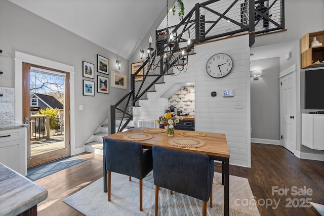 dining space featuring stairs, high vaulted ceiling, wood finished floors, and baseboards