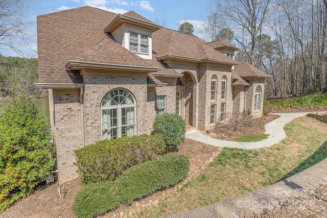 view of front of home with brick siding and roof with shingles