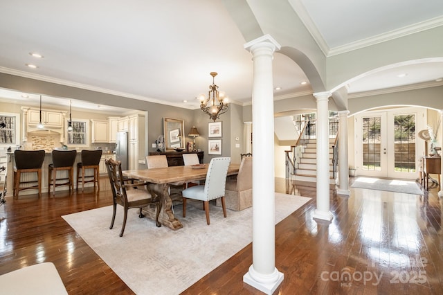 dining room featuring decorative columns, arched walkways, stairs, dark wood-type flooring, and french doors