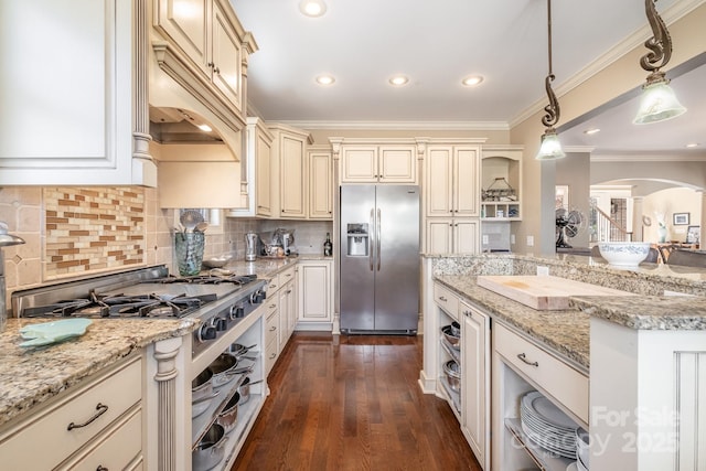 kitchen featuring crown molding, dark wood-style floors, arched walkways, cream cabinetry, and stainless steel appliances