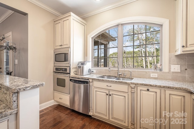 kitchen featuring a sink, crown molding, cream cabinets, and stainless steel appliances