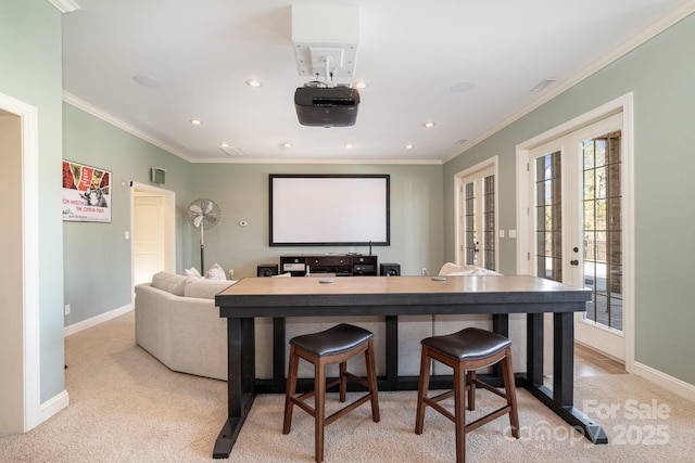 home theater room featuring crown molding, french doors, baseboards, and light carpet