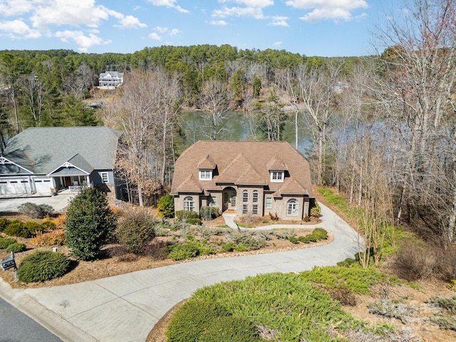 view of front of house with a view of trees and driveway