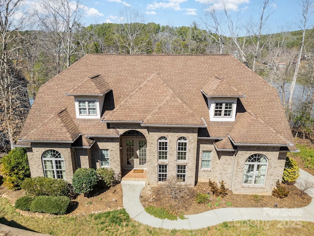 french provincial home with brick siding and roof with shingles