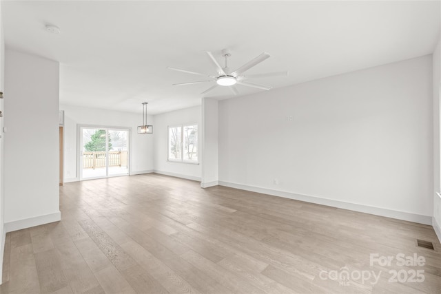 spare room featuring ceiling fan, light wood-style flooring, visible vents, and baseboards