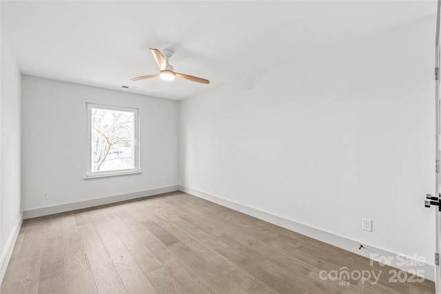 unfurnished room featuring a ceiling fan, wood finished floors, visible vents, and baseboards