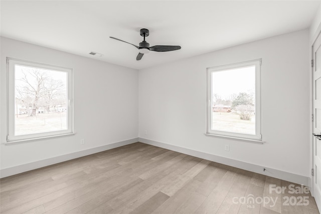 empty room with ceiling fan, light wood finished floors, visible vents, and baseboards