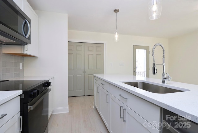 kitchen with white cabinets, backsplash, stainless steel appliances, and a sink