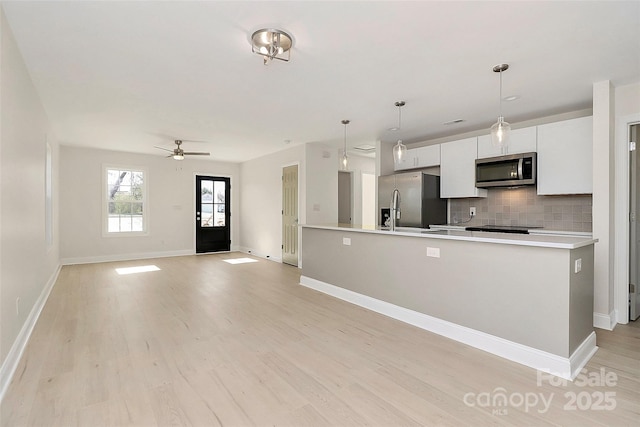 kitchen with stainless steel appliances, white cabinetry, light countertops, backsplash, and light wood finished floors