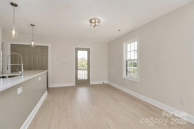 interior space with a sink, light wood-style flooring, and baseboards