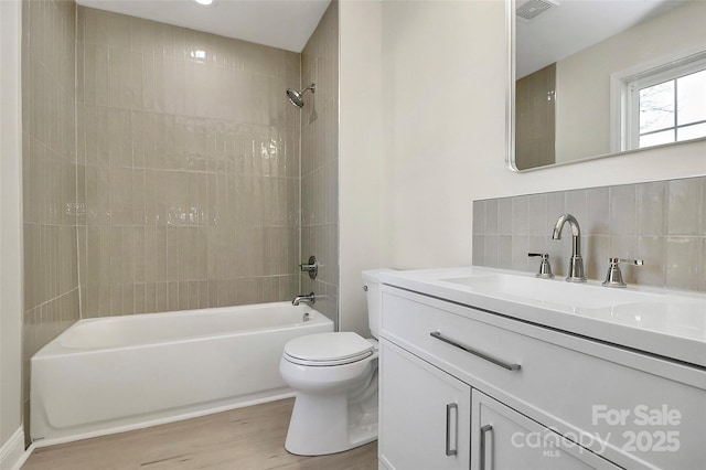 full bath featuring toilet, wood finished floors, visible vents, bathing tub / shower combination, and backsplash