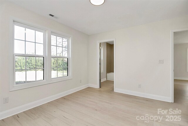 spare room with visible vents, light wood-style flooring, and baseboards