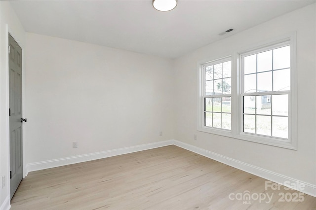 empty room featuring light wood-type flooring, visible vents, and baseboards