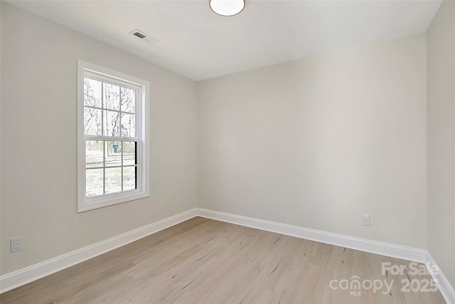 unfurnished room with light wood finished floors, visible vents, and baseboards