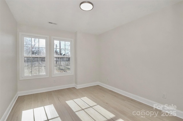 empty room with baseboards, visible vents, and light wood-style floors