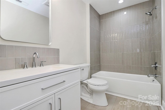 full bathroom with toilet, shower / bath combination, wood finished floors, vanity, and backsplash