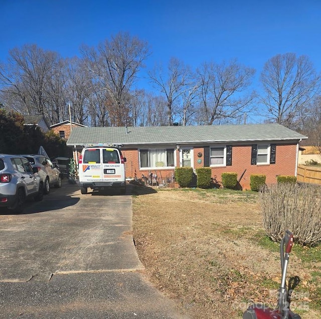 ranch-style home featuring a front yard, aphalt driveway, and brick siding