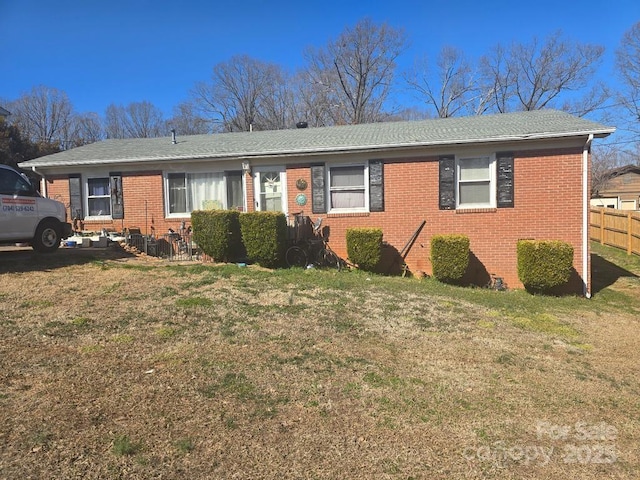 single story home featuring fence, a front lawn, and brick siding