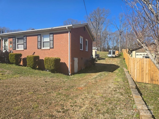 view of side of property featuring a yard, fence, and brick siding