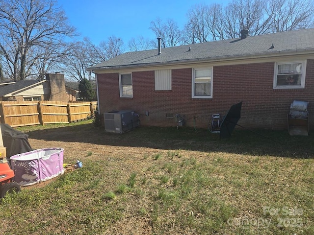 rear view of property featuring crawl space, fence, a lawn, and brick siding