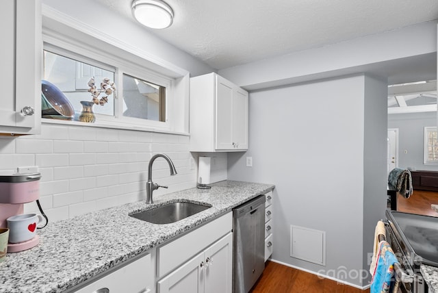 kitchen featuring a sink, light stone countertops, stainless steel appliances, white cabinetry, and backsplash