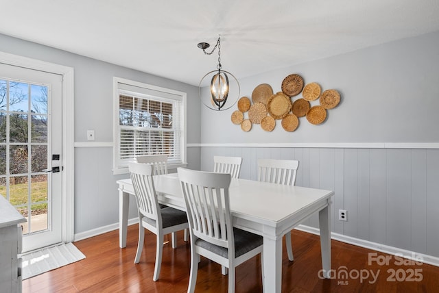 dining space with an inviting chandelier, plenty of natural light, and wood finished floors