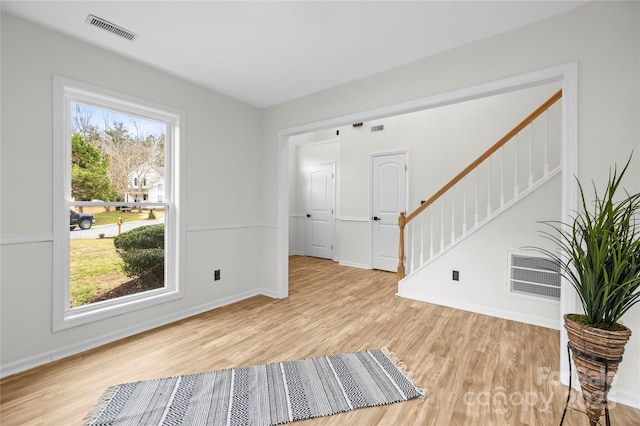 interior space featuring a wealth of natural light, visible vents, wood finished floors, and stairs