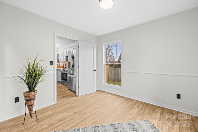 unfurnished room featuring baseboards and light wood-style flooring