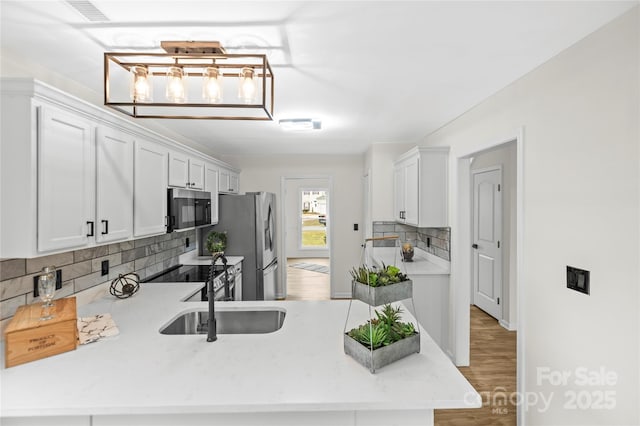 kitchen with decorative backsplash, white cabinets, stainless steel appliances, and a sink