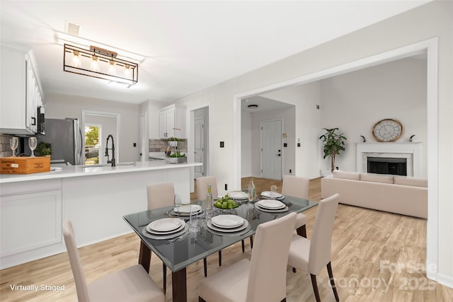 dining space featuring a high end fireplace, visible vents, and light wood-type flooring