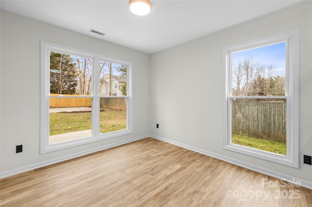 unfurnished room featuring visible vents, baseboards, and light wood-style floors