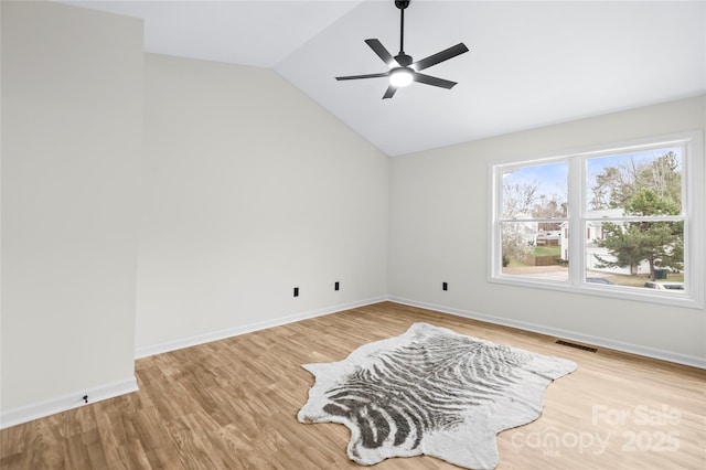 spare room featuring baseboards, lofted ceiling, and wood finished floors