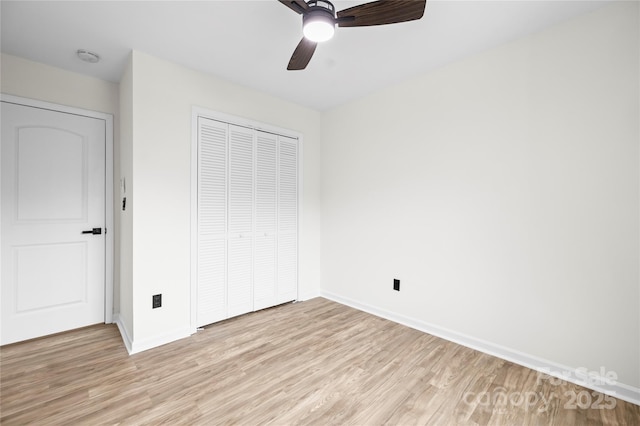 unfurnished bedroom featuring a ceiling fan, light wood-style floors, a closet, and baseboards