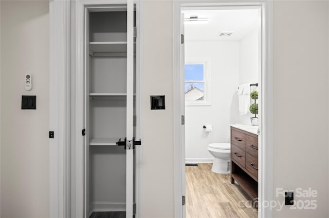 bathroom featuring vanity, toilet, wood finished floors, and visible vents