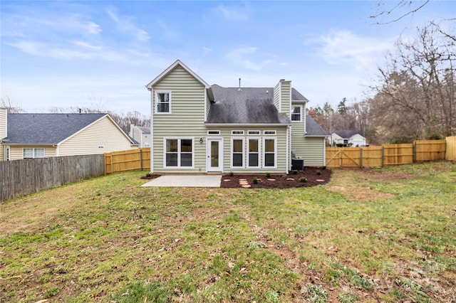 rear view of property featuring a patio area, a lawn, a chimney, and a fenced backyard