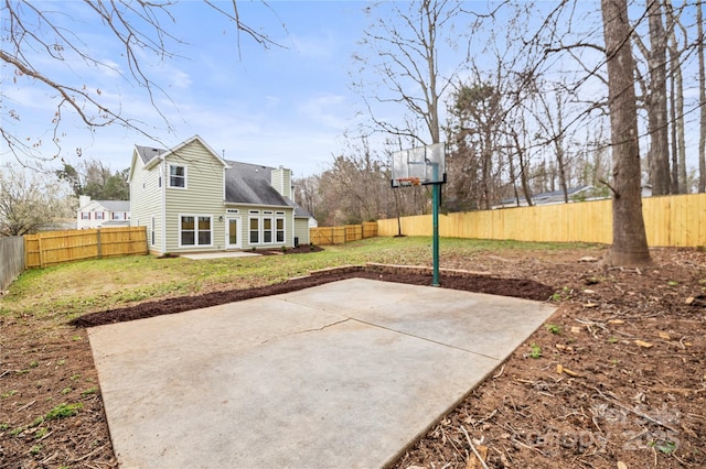 view of sport court with a fenced backyard and a lawn