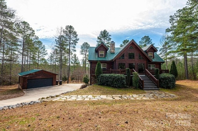 log cabin with an outbuilding, metal roof, a chimney, and a garage