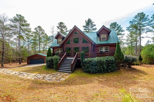 view of front of home with an outbuilding, metal roof, a detached garage, stairway, and a wooden deck