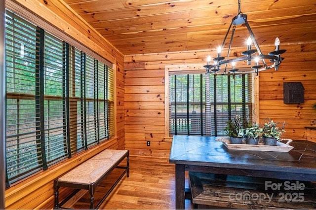 dining room featuring wooden ceiling, wood finished floors, an inviting chandelier, and wood walls