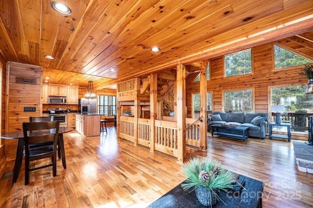 dining space with a notable chandelier, light wood-type flooring, wooden ceiling, and wooden walls