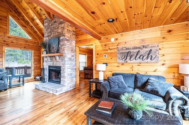 living area with a stone fireplace, wooden ceiling, wooden walls, wood finished floors, and beamed ceiling