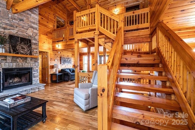 stairs with beam ceiling, a fireplace, wood ceiling, wood walls, and wood finished floors