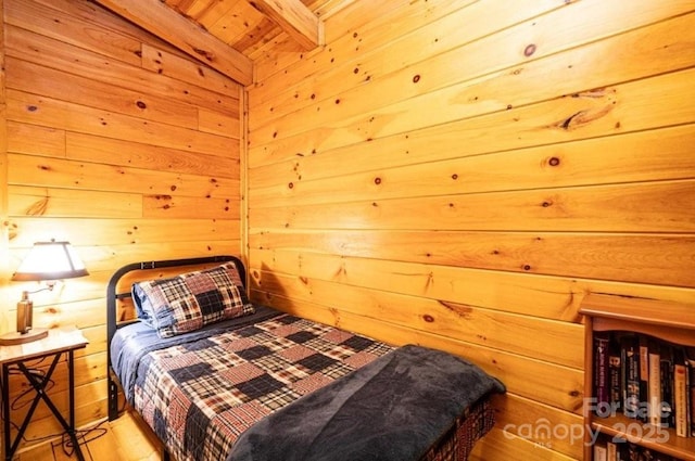 bedroom with beamed ceiling and wood walls