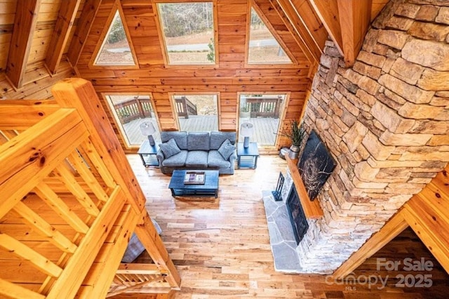 living area featuring a healthy amount of sunlight, wood walls, a fireplace, and wood finished floors