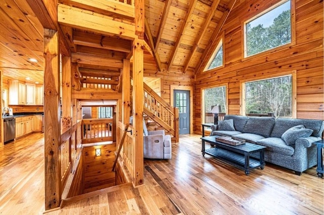 living area with wooden walls, wood ceiling, stairs, light wood finished floors, and beamed ceiling