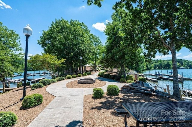 view of home's community featuring a boat dock, a water view, and a fire pit