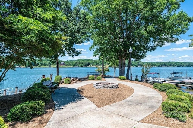 view of home's community with a dock, a water view, and a fire pit