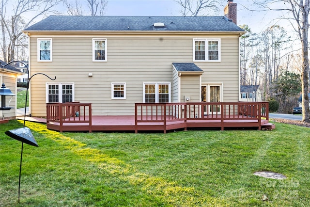 back of property featuring a deck, a shingled roof, a lawn, and a chimney