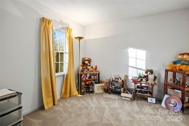 recreation room featuring a textured ceiling, carpet floors, and baseboards