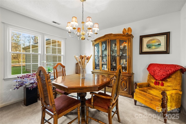 dining room with a textured ceiling, a chandelier, light carpet, visible vents, and baseboards